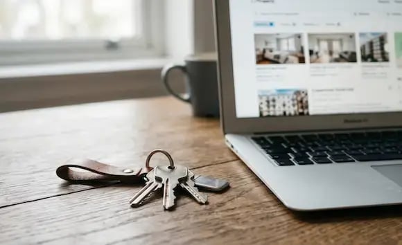 Apartment keys next to a laptop on a desk
