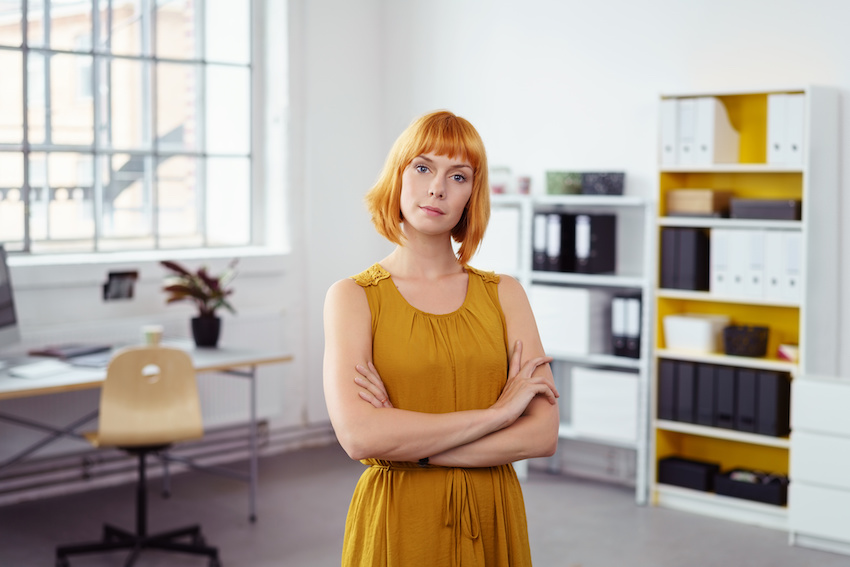 Frau im gelben Kleid steht im Büro
